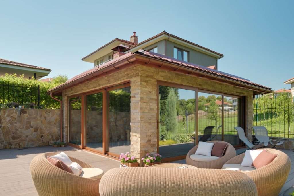 Modern Summer House Made Of Glass And Stone. Wicker Garden Furniture On A Wooden Terrace. expert sliding doors installation and repair services - 10