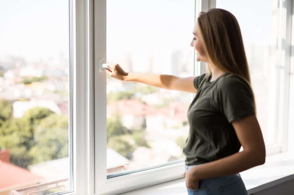 Young Woman Opening Window In Living Room At Home panoramalux - ontario's premier windows & doors company - 3